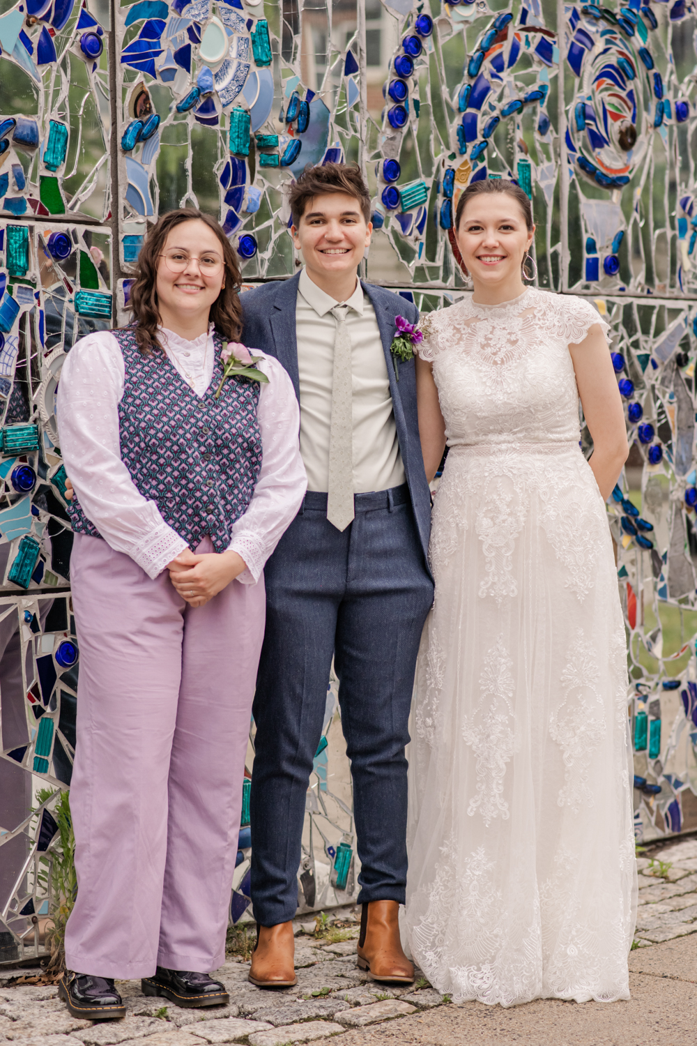 couple and wedding officiant in front of mosaic wall at AVAM
