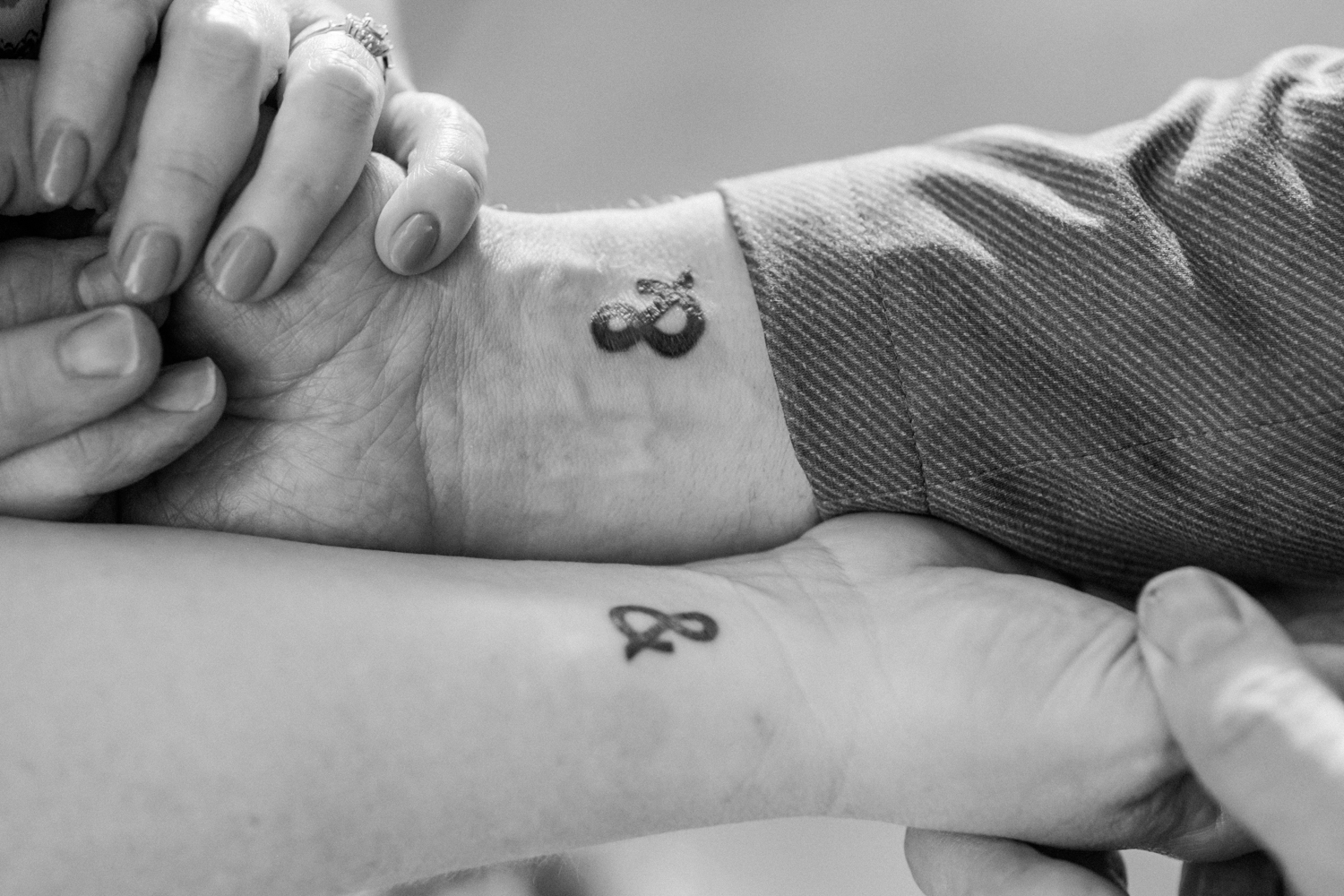 close up of ampersand tattoos on couples' arms
