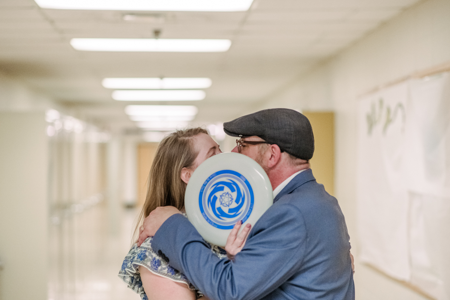 couple embraces behind frisbee inside