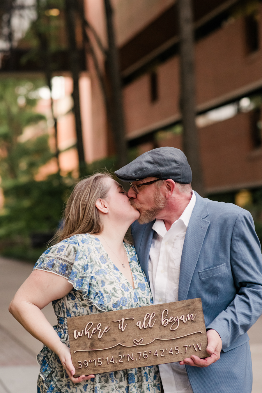 couple kisses holding "where it all began" sign at umbc