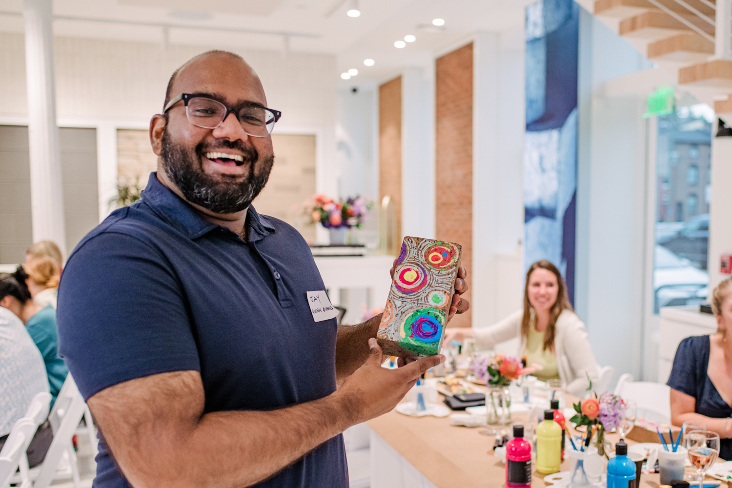 guest holds up painted brick and sip and paint night