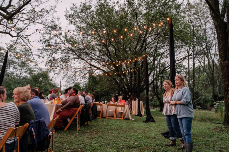 guests mingle at honey harvest event under string lights at twilight