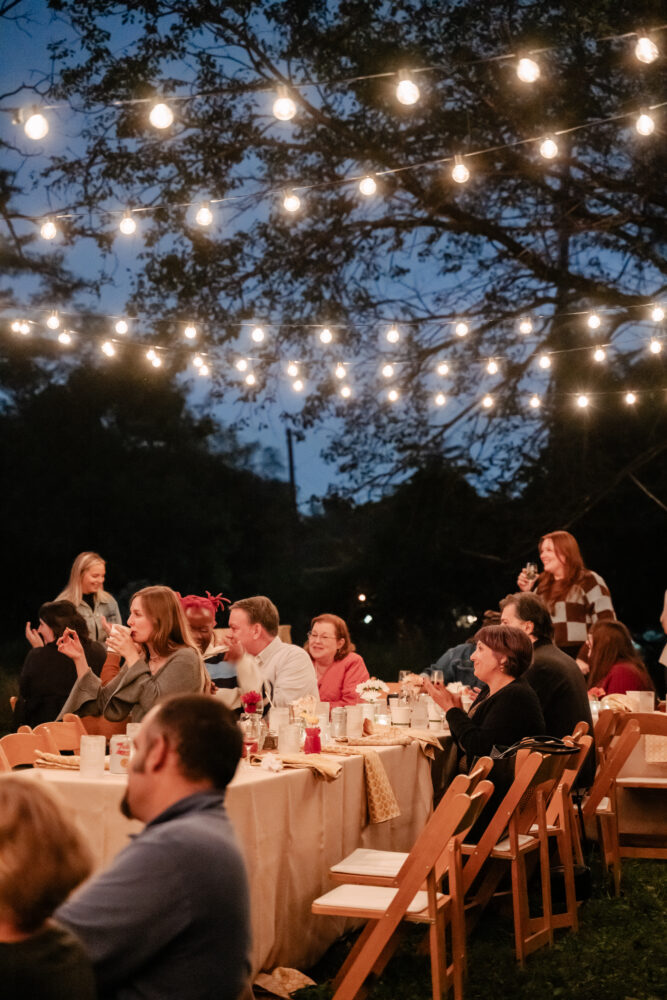 guests mingle at honey harvest event under string lights at twilight