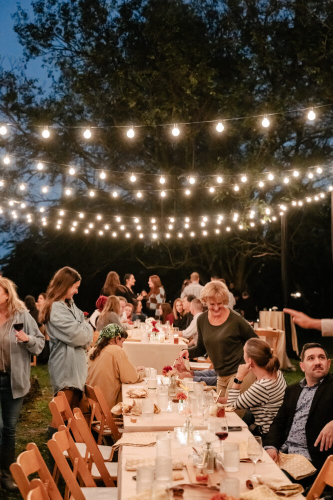 guests mingle at honey harvest event under string lights at twilight