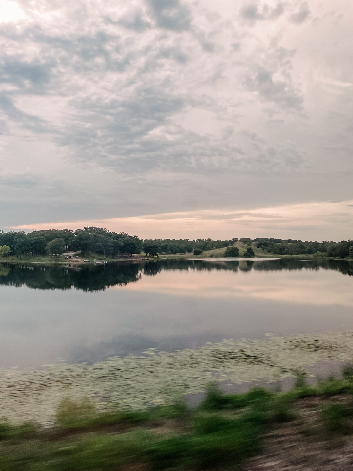 view of a body of water from train window at dusk
