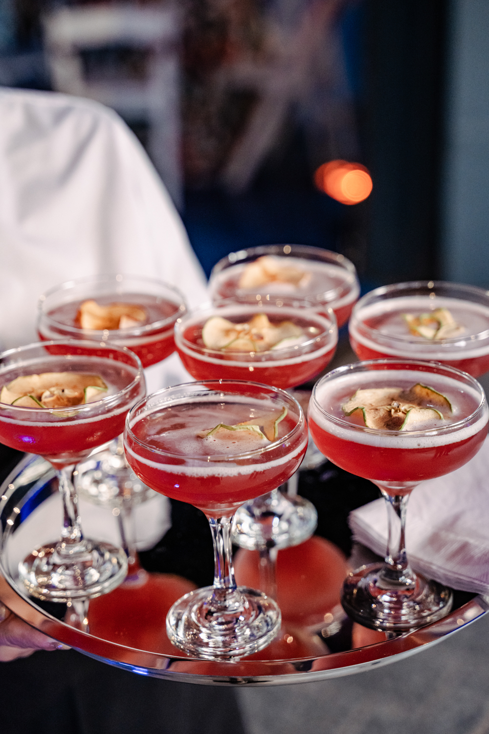 server holding tray of pink mocktails