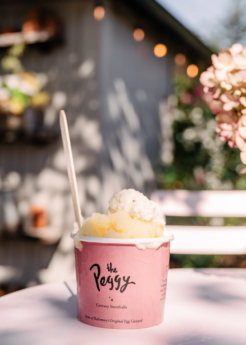 snowball in a "The Peggy" pink cup on an outdoor table